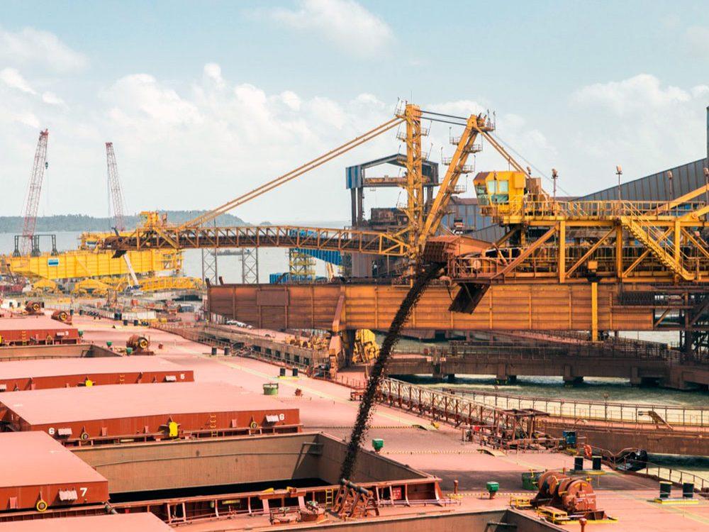 Carga de mineral a granel en un buque desde las grúas de un puerto de embarque